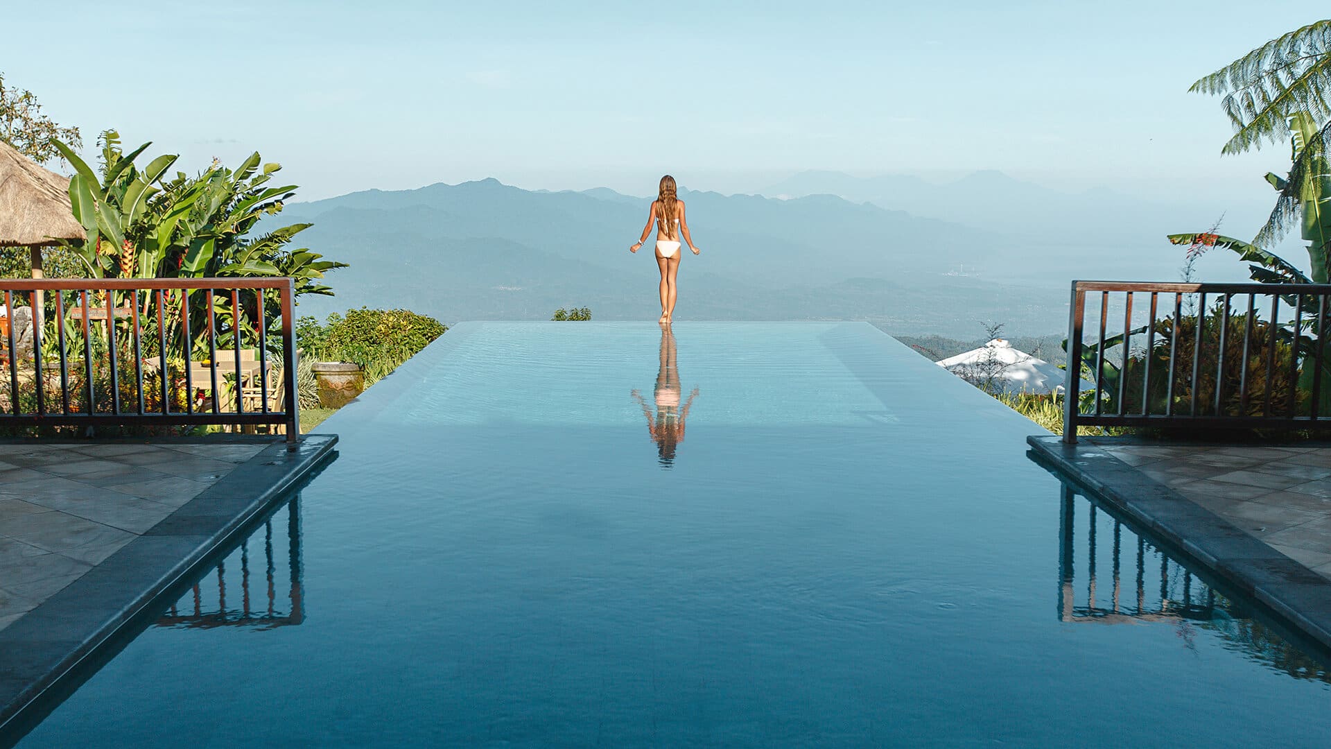 femme de dos devant une splendide piscine avec une vue magnifique