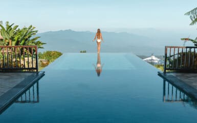 femme de dos devant une splendide piscine avec une vue magnifique
