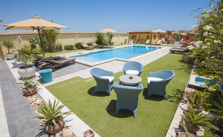 un très beau salon de jardin sur une pelouse avec une piscine en fond